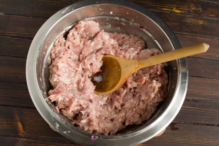 How to Properly Mix Ground Meat for Perfect Cutlets Hands kneading the ground meat mixture in a bowl to combine all ingredients.