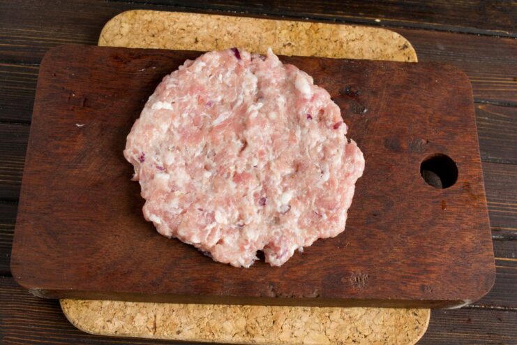Shaping the Meat Patties Before Stuffing A flat, round meat patty being formed by hand for stuffing.