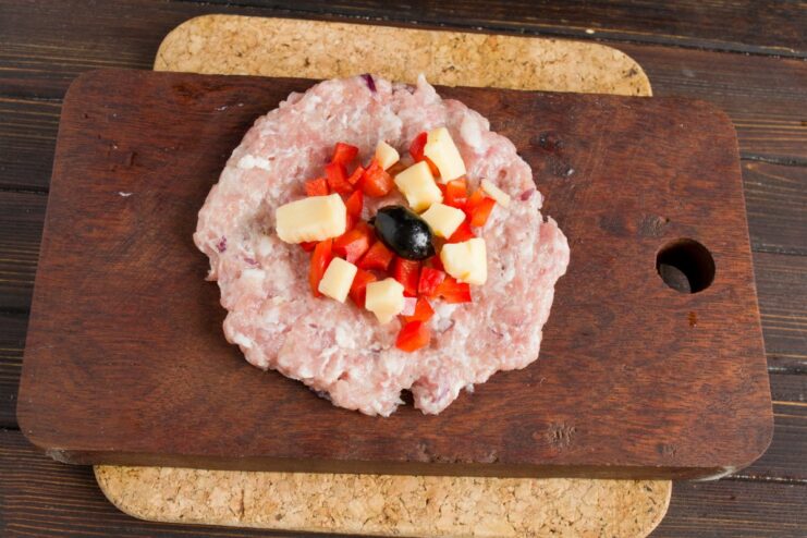 Creating the Savory Cheese and Olive Filling A pitted olive and cubes of cheese added on top of the bell pepper filling.