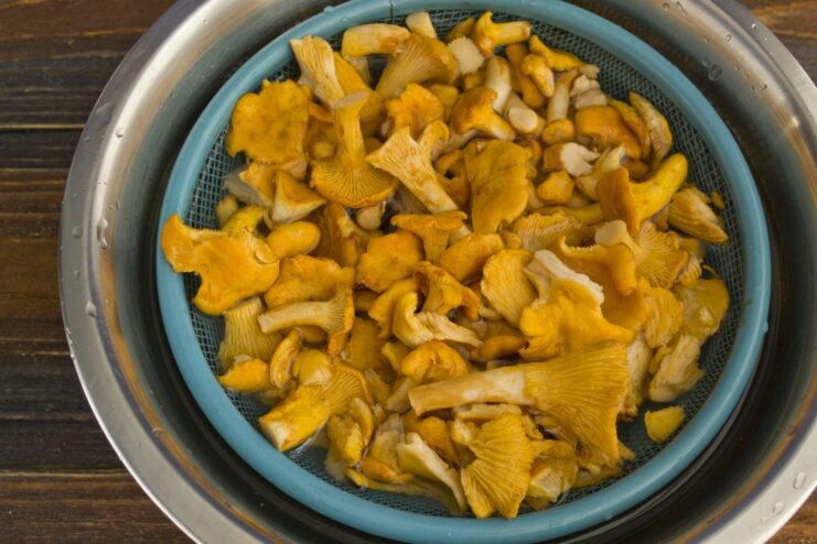 Step 1: Preparing the Chanterelles by Soaking and Washing Fresh chanterelle mushrooms in a white bowl with water, being cleaned.