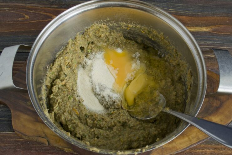 Binding the cutlet mixture with egg and semolina Adding a raw egg and semolina to the blended lentil mixture in a bowl.