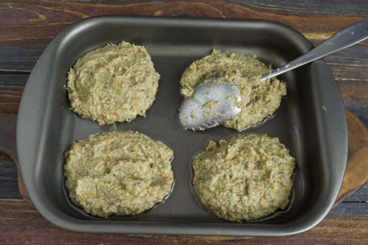Shaping the lentil and chanterelle cutlets before baking Shaped raw lentil and chanterelle cutlets arranged on a greased baking dish.