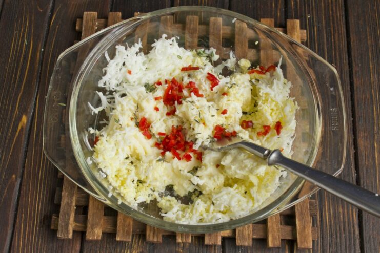 Preparing a Savory and Spicy Topping for Kotlety A bowl with ingredients for the topping: soft cheese, chopped egg, chili, and garlic.