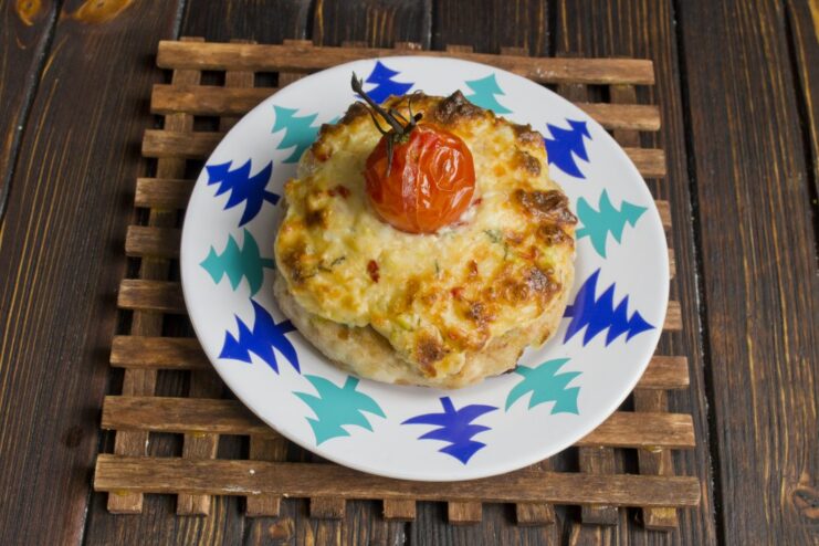 The Final Dish: Golden and Bubbly Oven-Baked Kotlety Freshly baked kotlety with a melted, golden topping and roasted cherry tomatoes.
