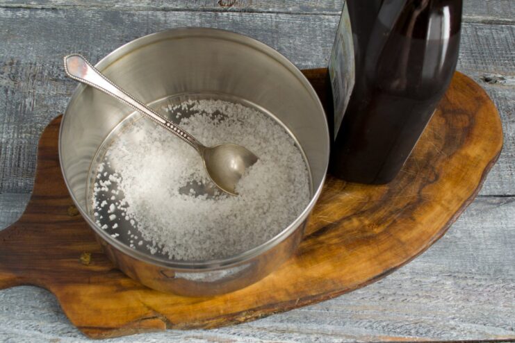 Starting the brine with a base of coarse sea salt. Coarse sea salt being poured from a hand into a stainless steel pot for the brine.
