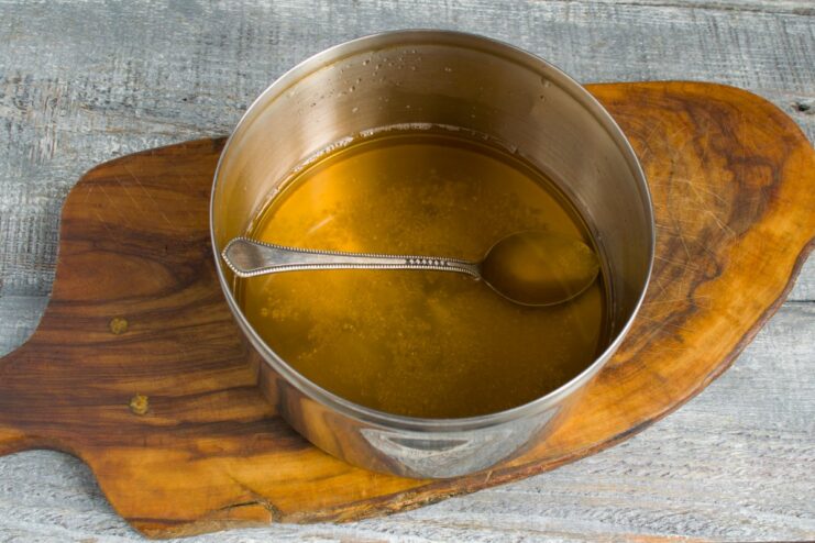 Adding liquid smoke and water to create the flavorful marinade. Pouring liquid smoke and warm water into a pot of salt to create the smoky brine.