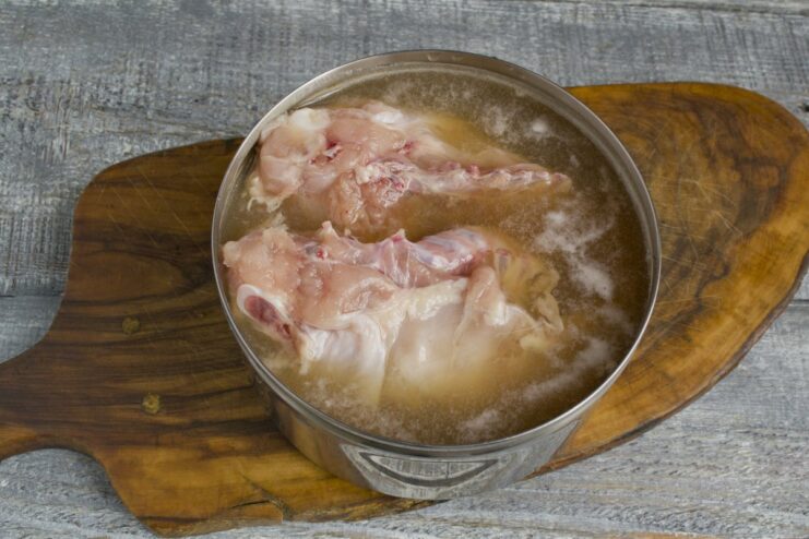 Letting the chicken marinate for 24 hours to absorb all the smoky goodness. A chicken breast fully submerged in a dark brine inside a pot, set to marinate.