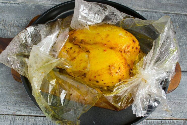 Baking the chicken in a roasting bag to lock in moisture and flavor. A roasting bag containing chicken and onions on a baking sheet, ready for the oven.