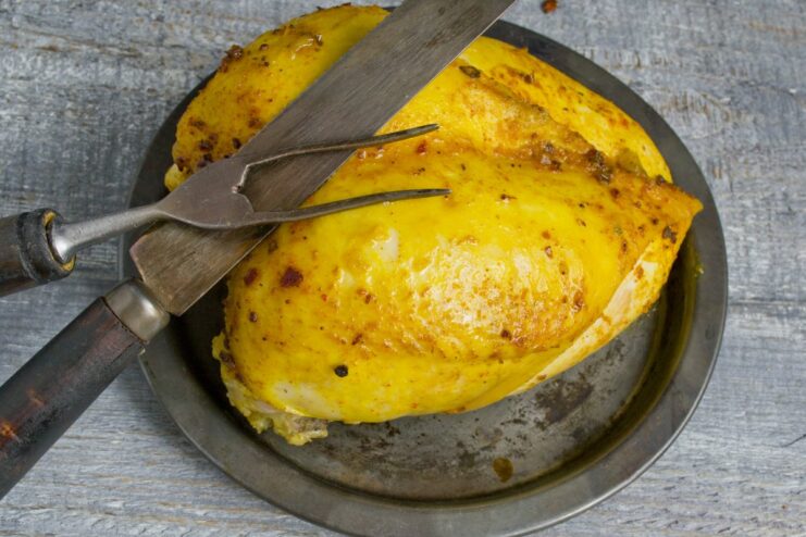 Perfectly sliced oven-baked chicken with a smoky flavor. A plate of sliced oven-baked chicken breast, cooked with liquid smoke, ready to serve.