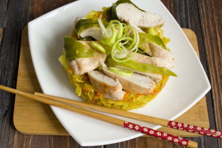 The finished dish: perfectly steamed chicken with flavorful stewed cabbage. The final dish served on a plate: sliced steamed chicken on a bed of stewed cabbage.