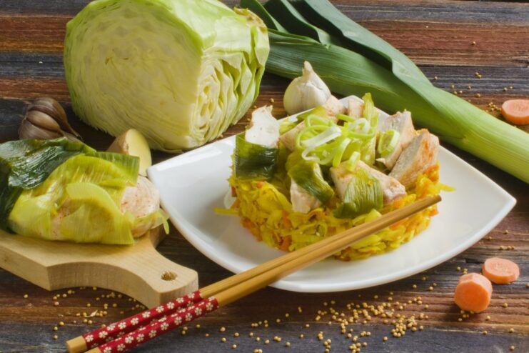 A plate of steamed chicken fillet served with a side of stewed cabbage and vegetables.