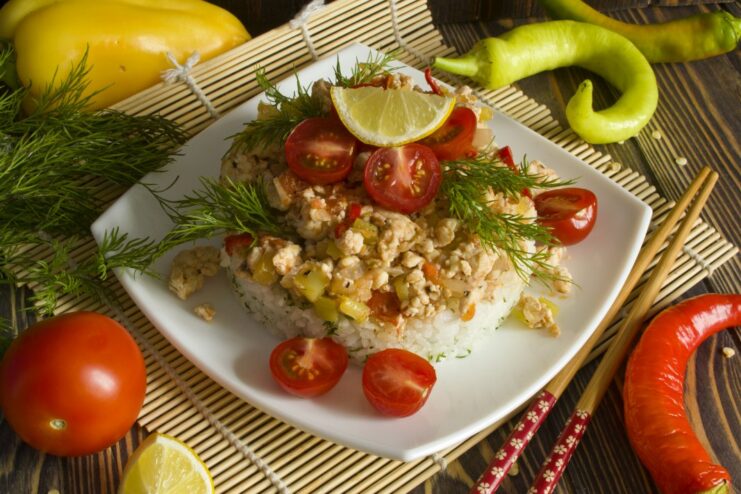A plate of Korean-style chicken fillet with rice and vegetables, garnished with fresh herbs.