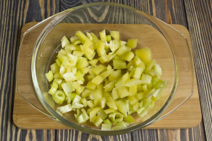 Adding colorful bell peppers and green chili for flavor and crunch Diced bell peppers and green chili being stir-fried in a wok.