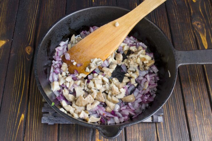 Adding Earthy Flavor: Cooking Wild Mushrooms with Onions Chopped cooked wild mushrooms being sautéed with onions in a skillet.