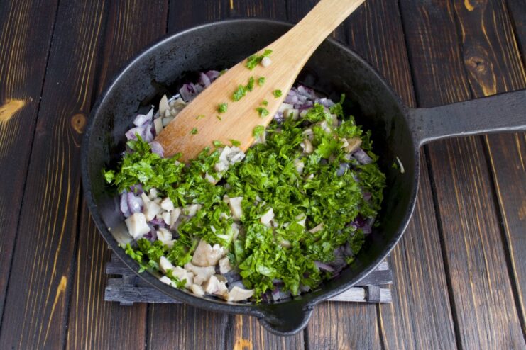 Finishing the Filling with Fresh Herbs for Extra Aroma Chopped fresh parsley being added to the skillet with sautéed mushrooms and onions.