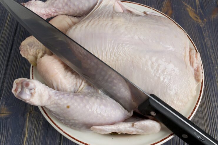 How to Butcher a Chicken for Making Minced Meat A whole young chicken on a cutting board being prepared for butchering.