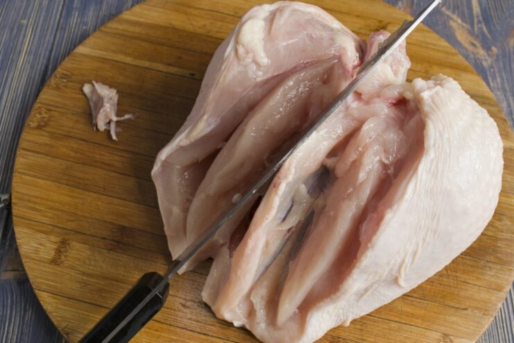 Step-by-Step: Deboning Chicken for Homemade Meatballs Chicken pieces being deboned and skin removed on a cutting board.
