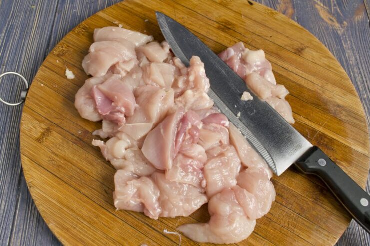 Chopping Chicken Meat into Small Cubes for Grinding Diced chicken breast and thigh meat on a cutting board.