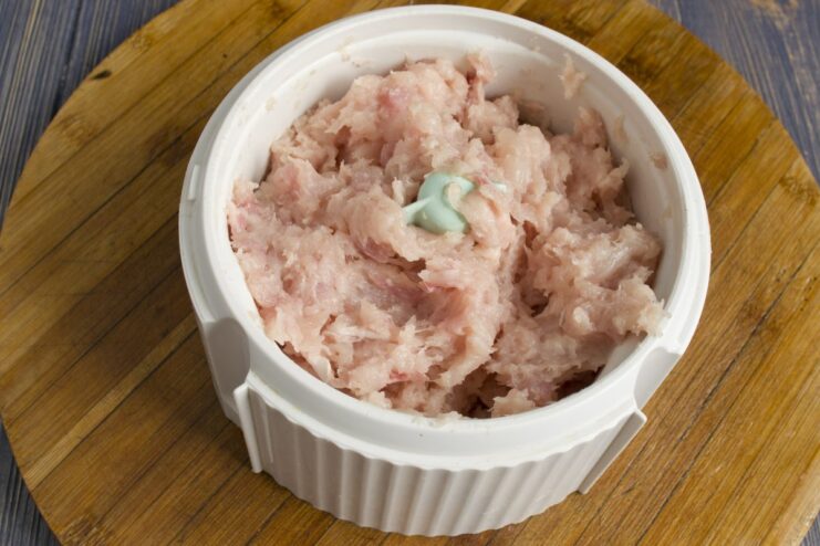 Using a Blender to Mince Chicken for Tender Meatballs Chicken meat being minced in a food processor or blender.