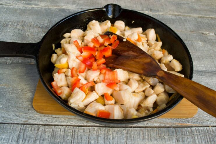 Creating the Sweet and Sour Sauce in the Pan Chicken and vegetables being stir-fried in a skillet as soy sauce and other sauce ingredients are poured in.