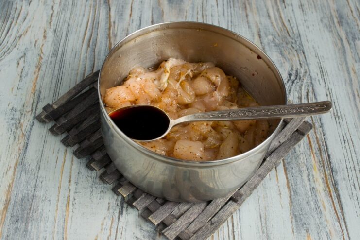 Step 1: Marinating the Chicken for Maximum Flavor A bowl of sliced raw chicken fillet being marinated in a dark soy sauce mixture.