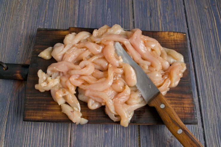Seasoning Chicken for Maximum Flavor Raw chicken fillet strips in a bowl, seasoned with salt and ground paprika.
