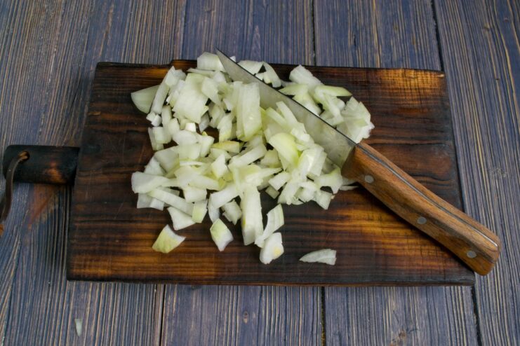 Building the Flavor Base with Onions Finely chopped white onion being sautéed in a skillet until soft.