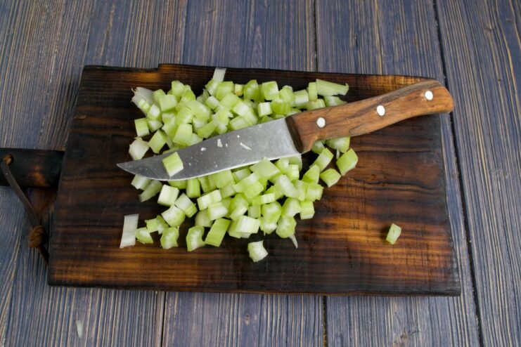 Adding Celery for a Fresh Crunch Diced celery being added to the skillet with sautéed onions.