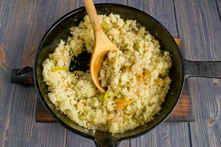 Combining Couscous with Sautéed Vegetables Steamed fluffy couscous being added to a skillet of colorful sautéed vegetables.