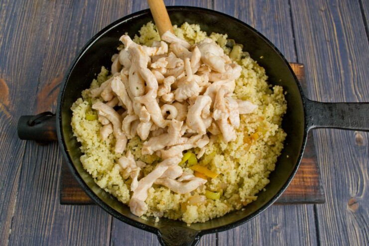 Bringing It All Together with Chicken Fried chicken strips being added to the skillet with couscous and vegetables.