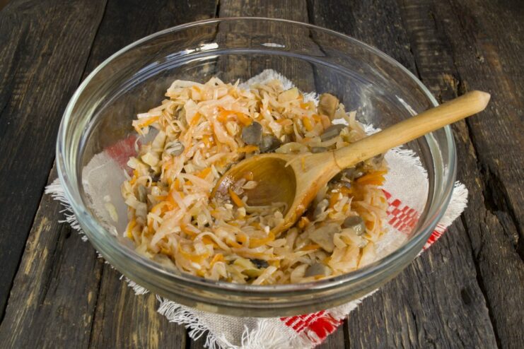 Step 1: Start with a jar of mushroom and cabbage solyanka A glass bowl being filled with mushroom and cabbage solyanka from a jar.