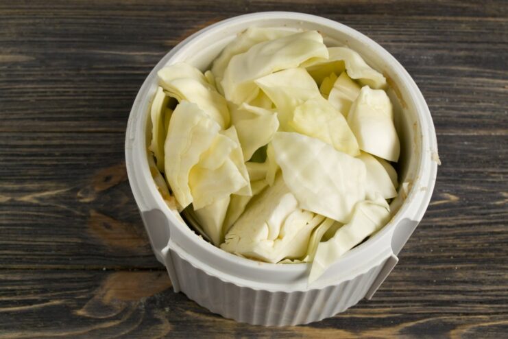 Finely Shredding Cabbage for the Cabbage Roll Mixture A pile of finely shredded white cabbage on a cutting board.