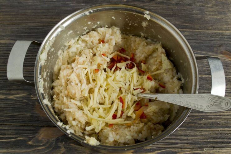 Enriching the Filling with Cheese and Bell Pepper Grated cheese and diced sweet bell pepper being added to the meat and vegetable mixture in a bowl.