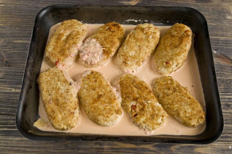 Covering the Cabbage Rolls with Flavorful Tomato Sauce Creamy tomato sauce being poured over the lazy cabbage rolls in a baking dish.