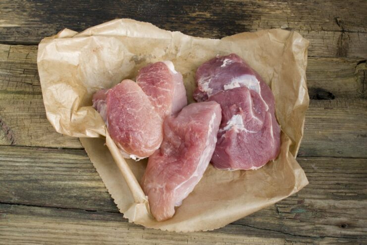 Select lean pork cuts like loin or shoulder for healthier patties. Raw lean cuts of pork on a cutting board, being prepared for grinding.