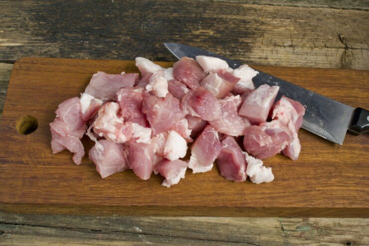 Dicing lean pork and a small amount of fat for juicy patties. Diced pork meat and a small amount of pork fat in a bowl, ready for the food processor.