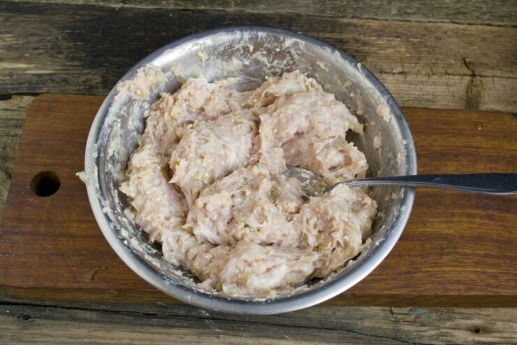 Let the meat mixture rest in the fridge to let the flavors meld. A bowl of well-mixed ground meat for patties, covered and ready for chilling.