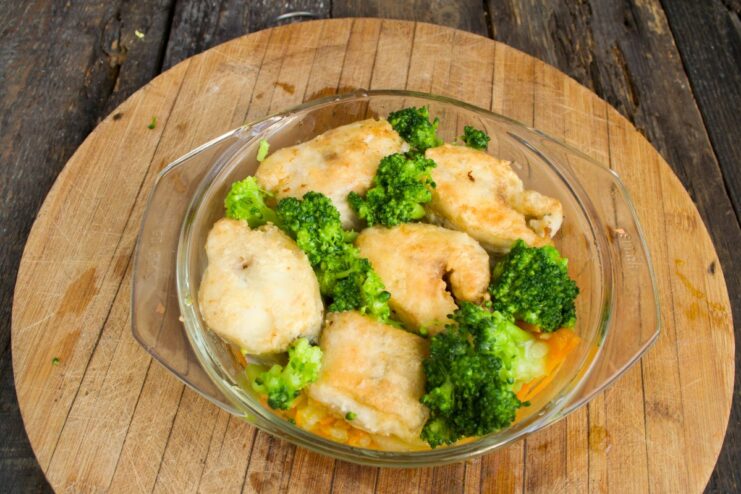 Adding Fresh Broccoli Florets for Extra Flavor and Nutrients Broccoli florets being added to the baking dish with pollock and vegetables.