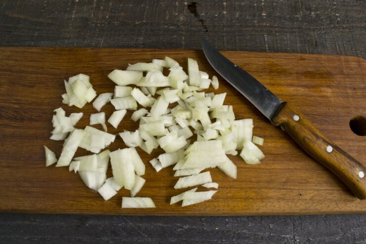 Finely Chopping Onions for the Sauce Base Finely chopped yellow onion on a cutting board.
