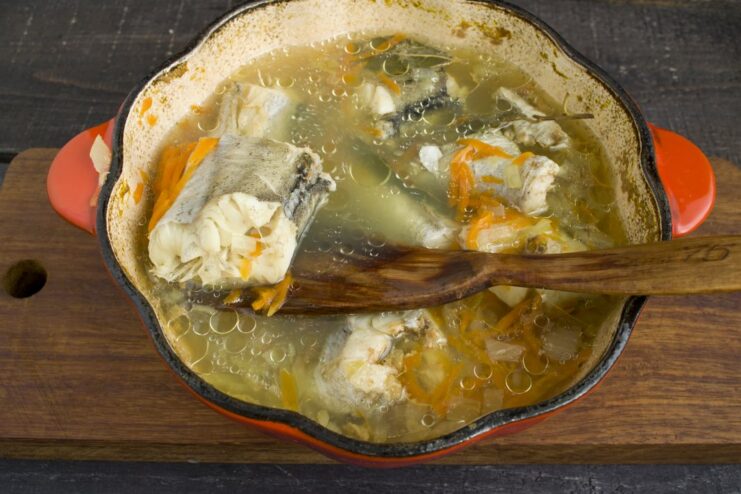 Simmering the Fish and Vegetables to Perfection A covered pot simmering on a stove, cooking the fish and vegetables.