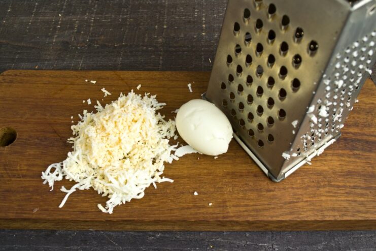 Grating Hard-Boiled Eggs for the Creamy Sauce A hard-boiled egg being grated on a fine grater.