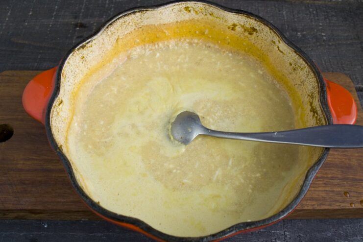 Finishing the Rich and Creamy Polish-Style Sauce Grated eggs and cream being stirred into the vegetable sauce in a pot.