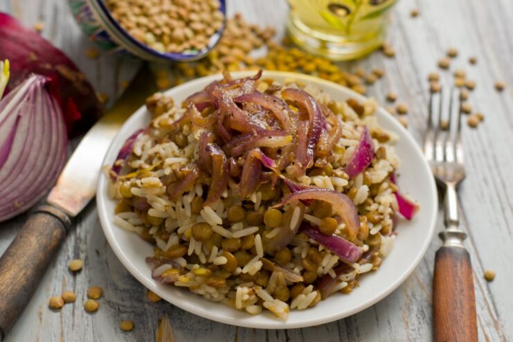 A bowl of freshly made Mujadara, a dish of lentils and rice, topped with fried onions.