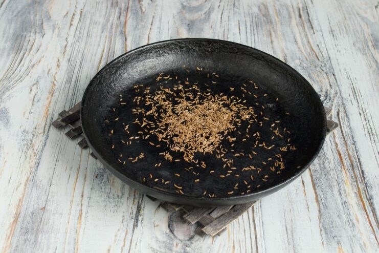 Toasting whole cumin seeds in a dry pan to release their aroma Cumin seeds being toasted in a hot, dry frying pan.