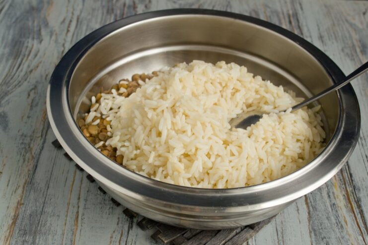 Mixing cooked rice and lentils together in a large bowl A large bowl containing cooked white rice and green lentils.