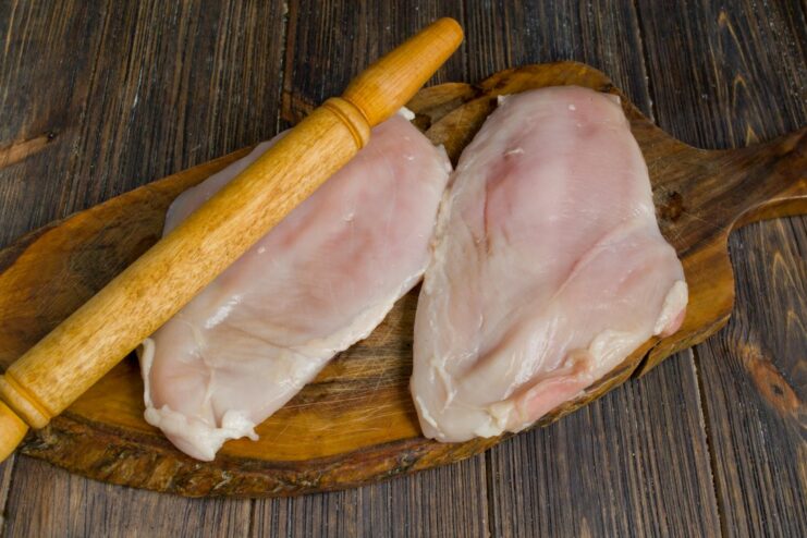 Two chicken fillets being seared in a hot pan after being pounded.