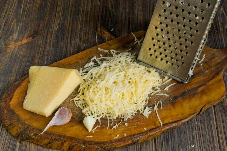 A bowl of grated hard cheese mixed with minced garlic.