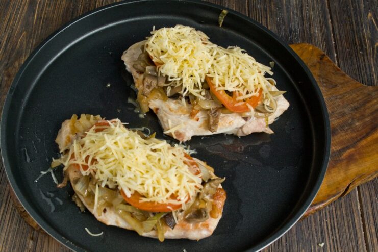 Chicken cutlets topped with mushrooms, onions, tomato slices, and a generous layer of grated cheese.