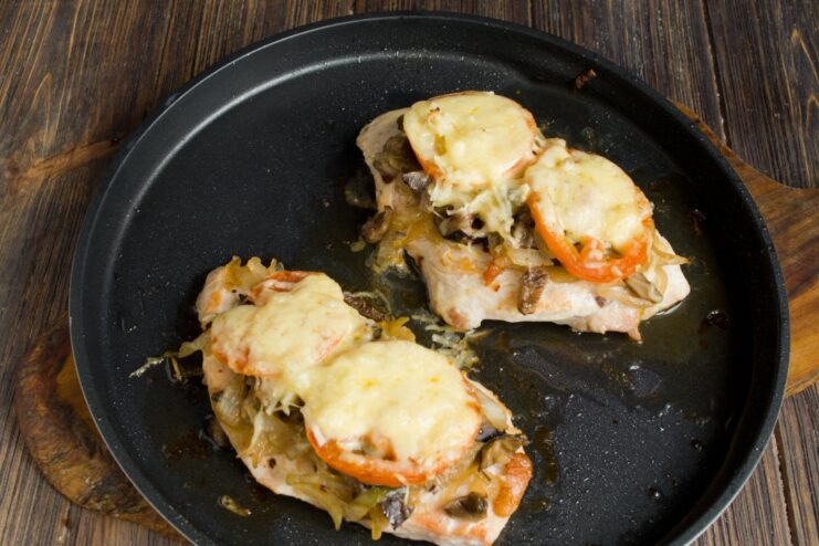 A baking sheet with chicken cutlets baking in the oven, with the cheese melting and turning golden.