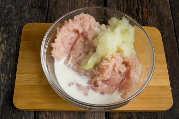 How to Make Juicy Chicken Meatball Mixture A bowl with ground chicken, grated onion, and cream for making meatballs.